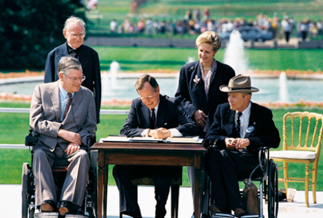 President George H. W. Bush signs the Americans with Disabilities Act of 1990 into law. (Image Credit: WikiMedia Commons)